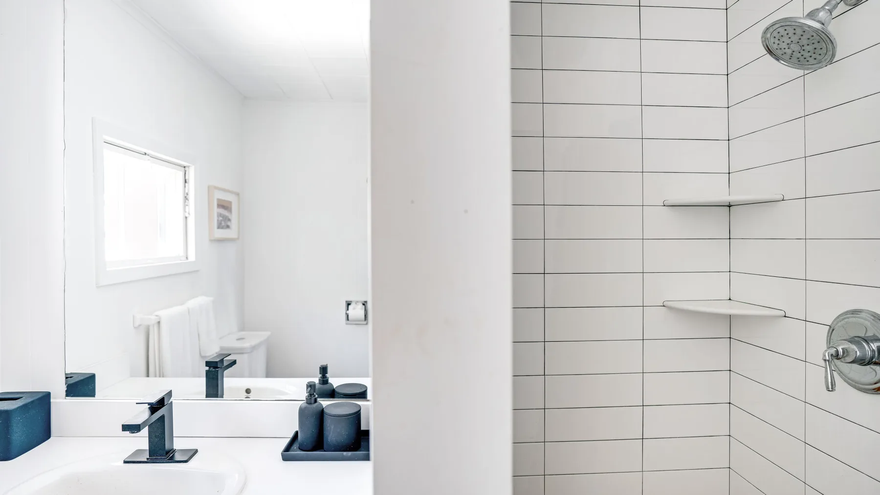 Un baño luminoso con lavabo y ducha de azulejos.