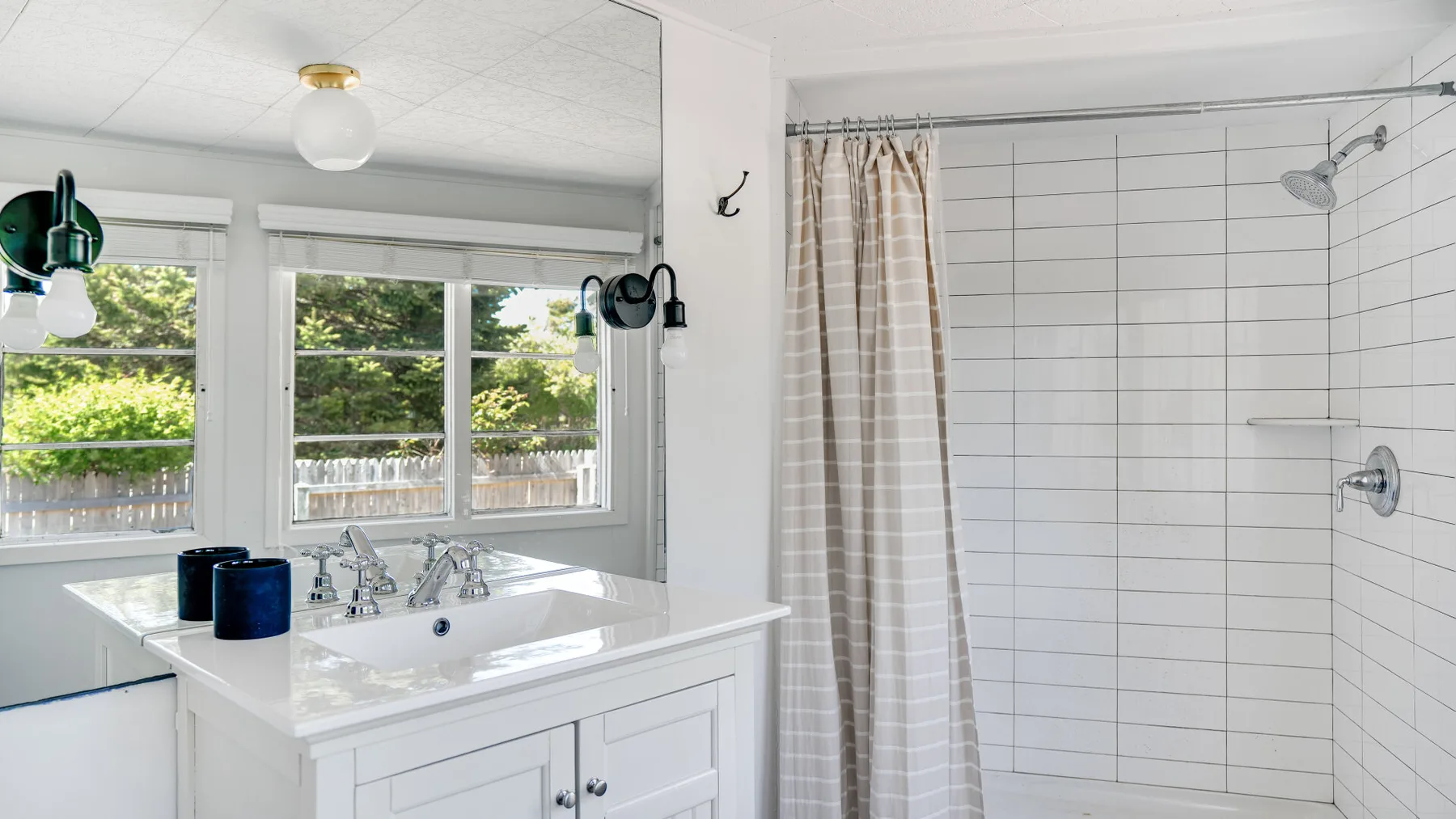 Un baño luminoso con un lavabo blanco y una ducha alicatada.