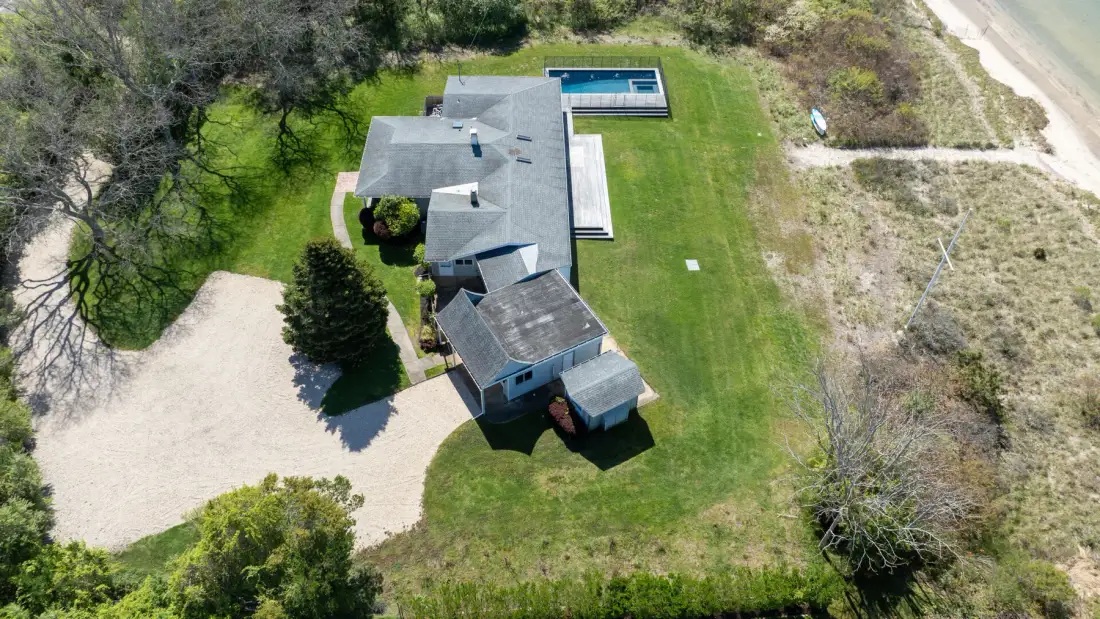 Una vista aérea muestra una casa junto a una piscina rectangular y un césped.