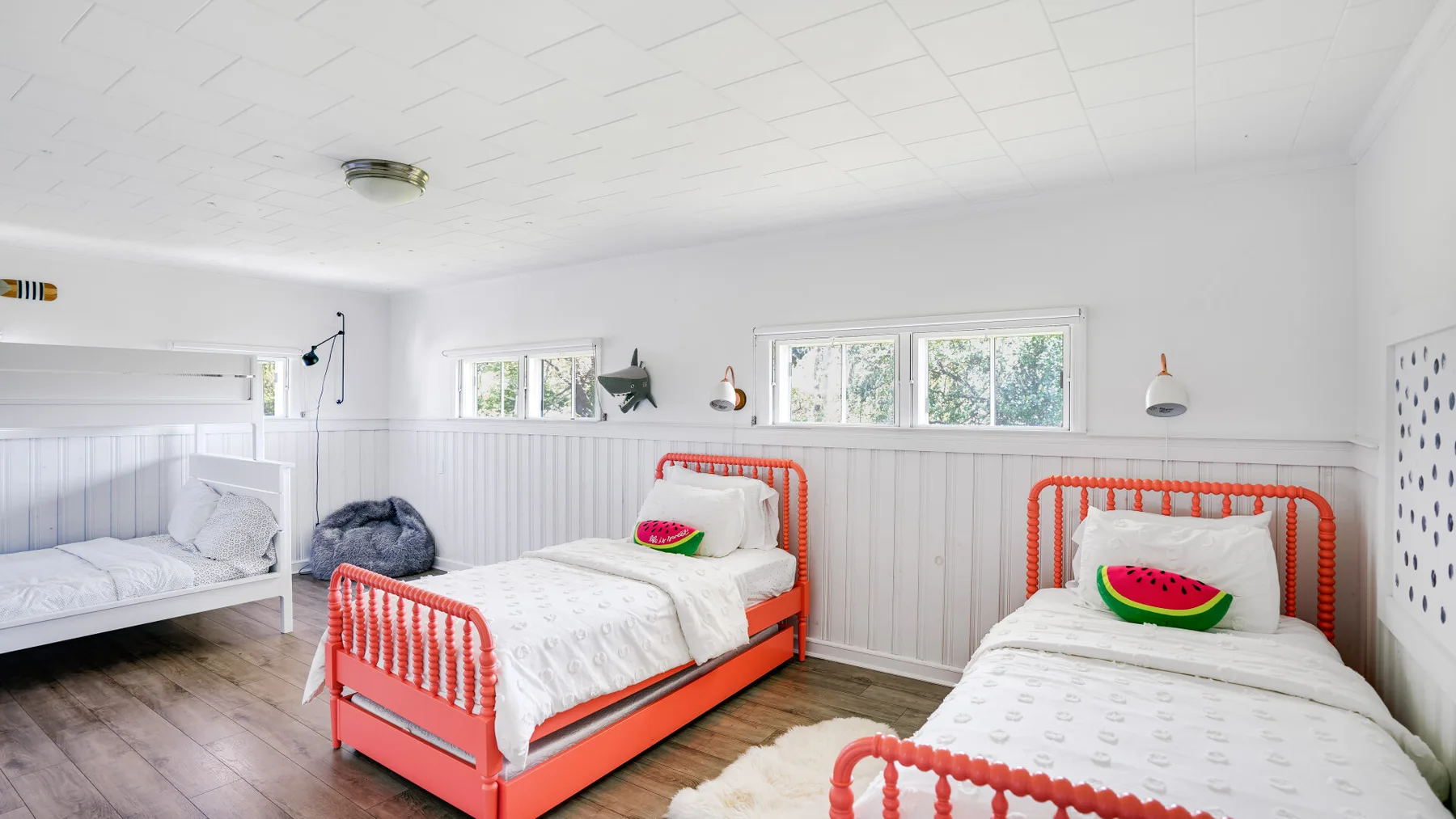 Un dormitorio luminoso con tres camas y ropa de cama colorida.