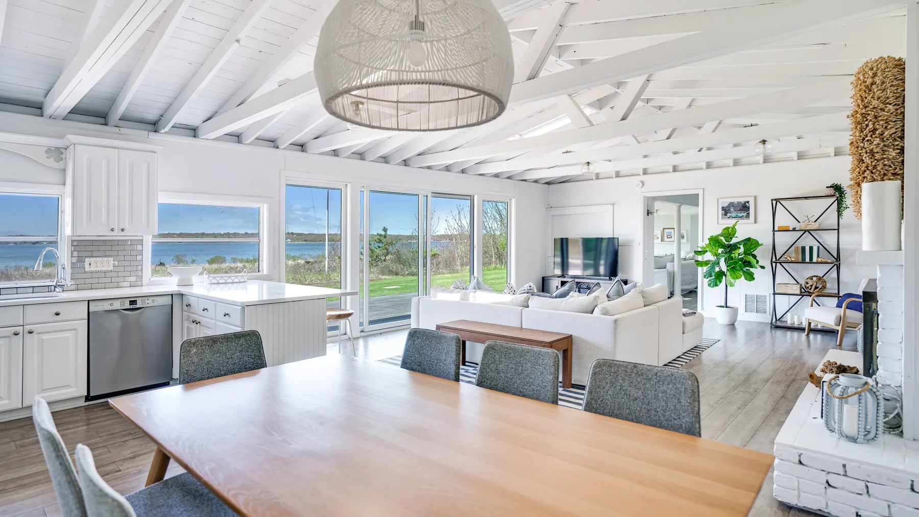 Una luminosa sala de estar y comedor diáfanos tiene grandes ventanas con vistas al agua.
