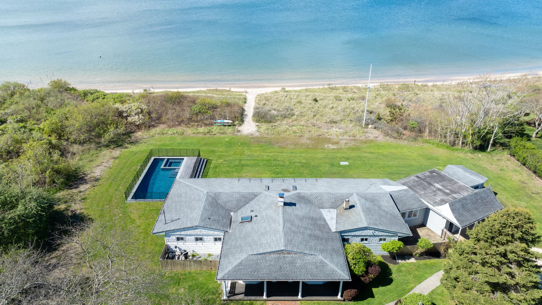 Vista aérea de una casa junto al mar, con piscina y el océano al fondo.