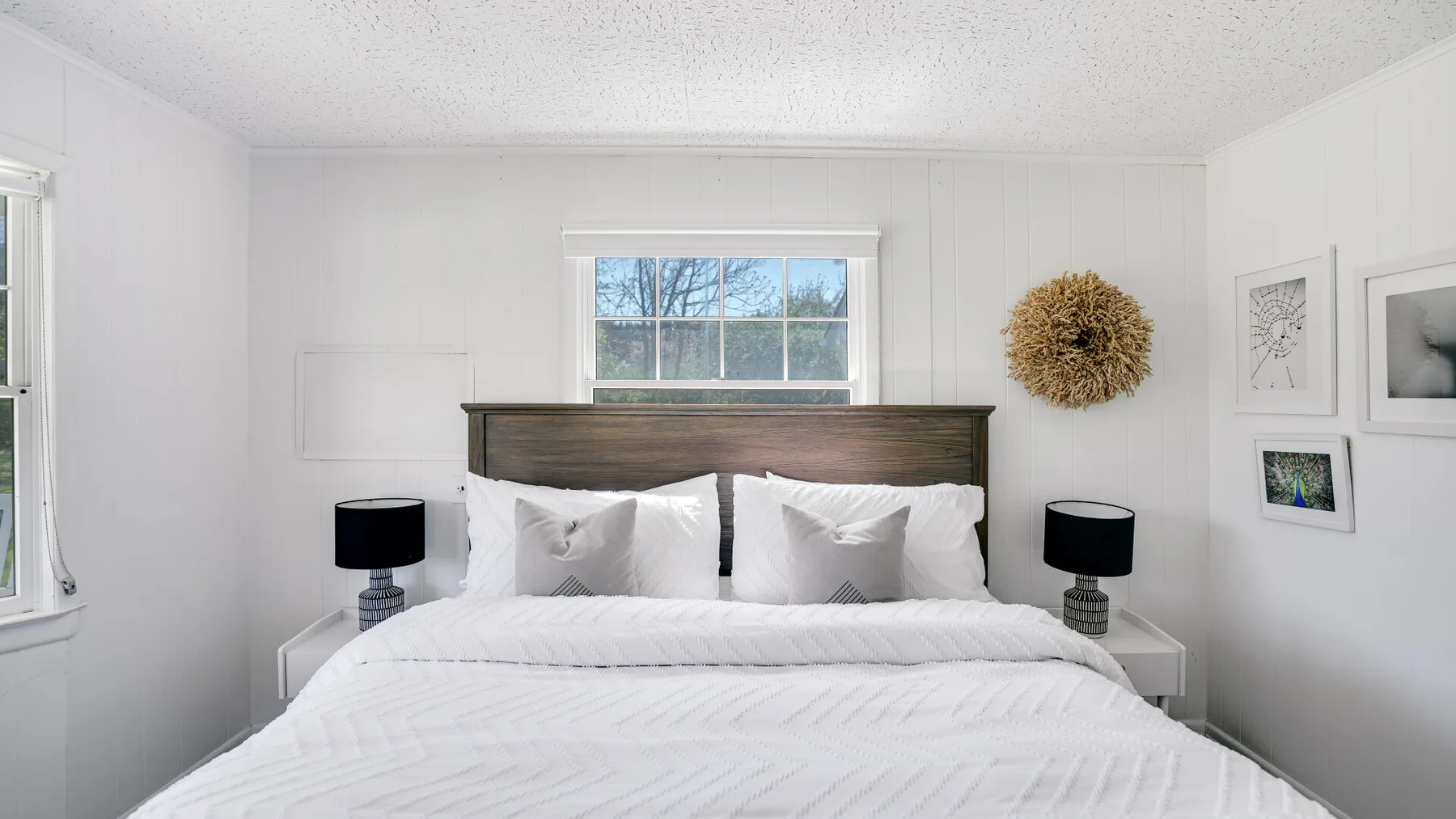 Un dormitorio luminoso con una cama bien tendida y una ventana detrás del cabecero.