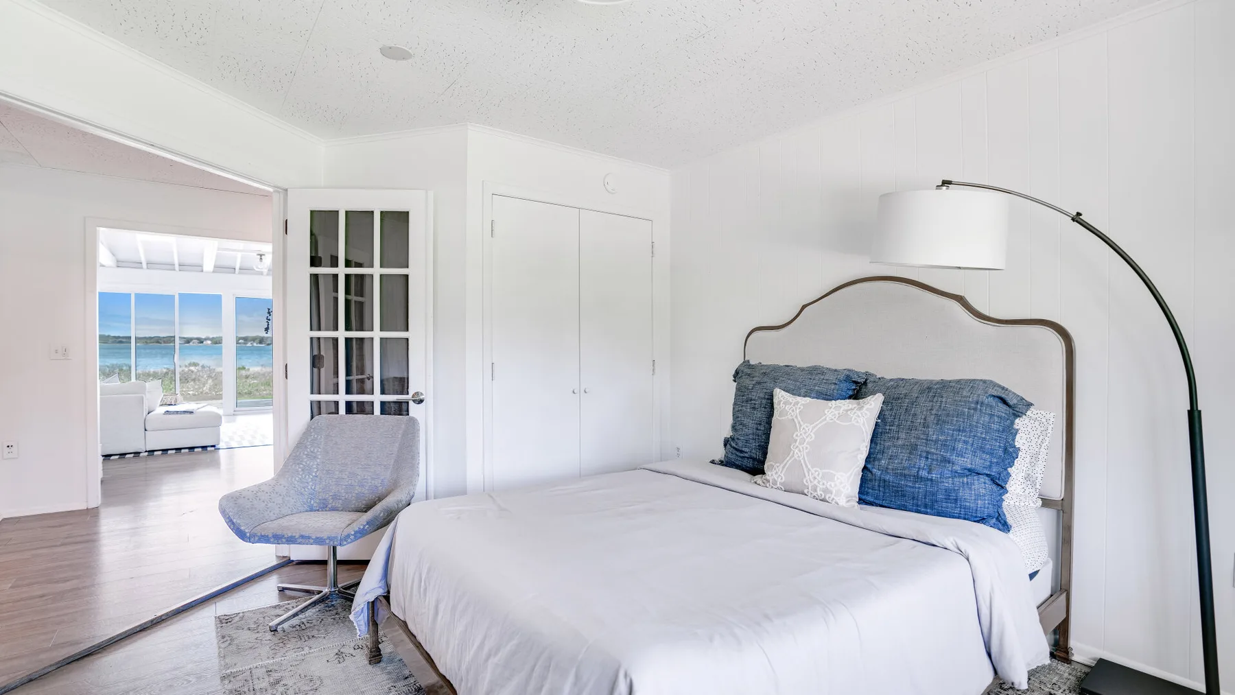 Un dormitorio luminoso con una cama tendida y una zona de estar junto a la ventana.