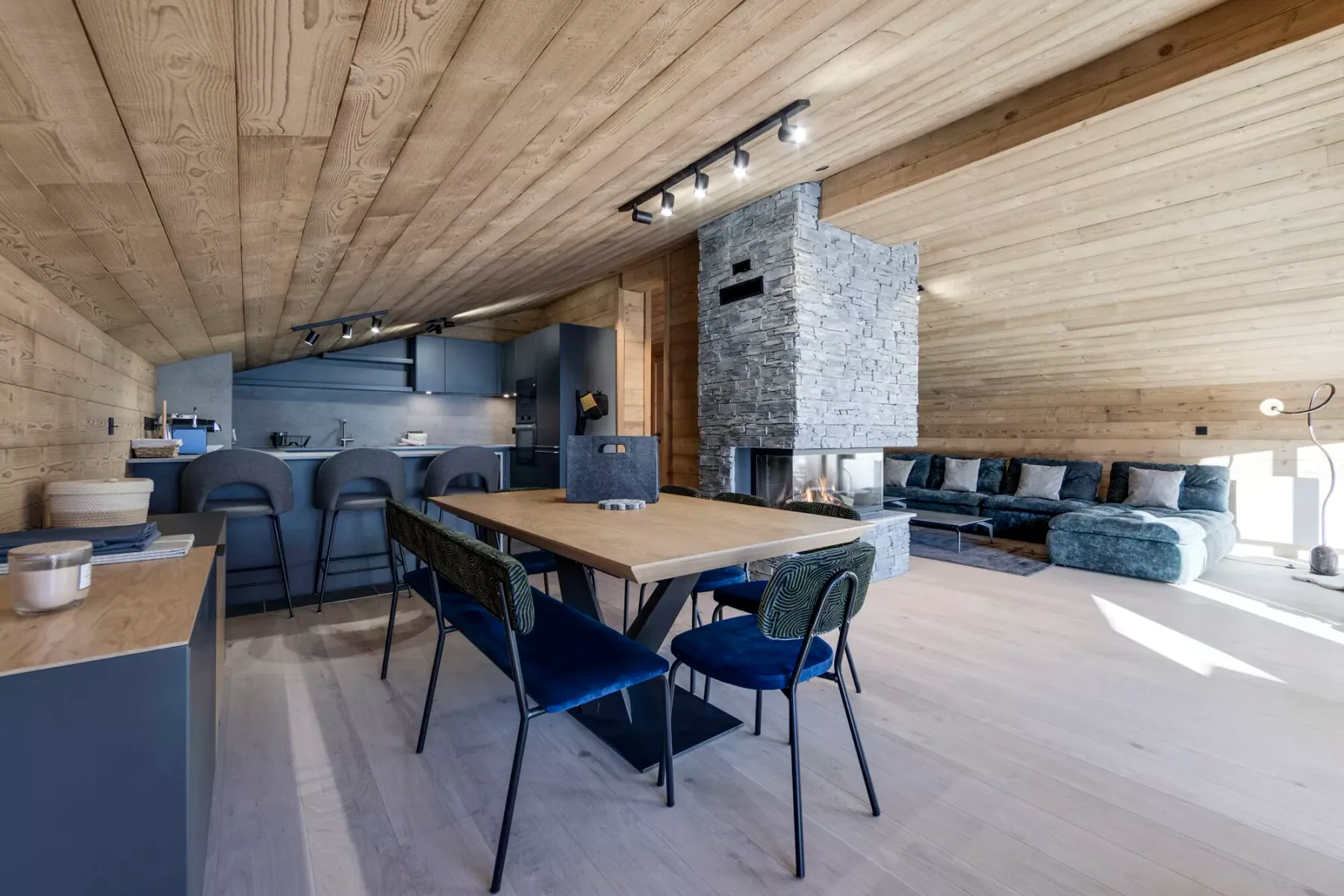 An open-plan living and dining area with a kitchen and a stone fireplace.