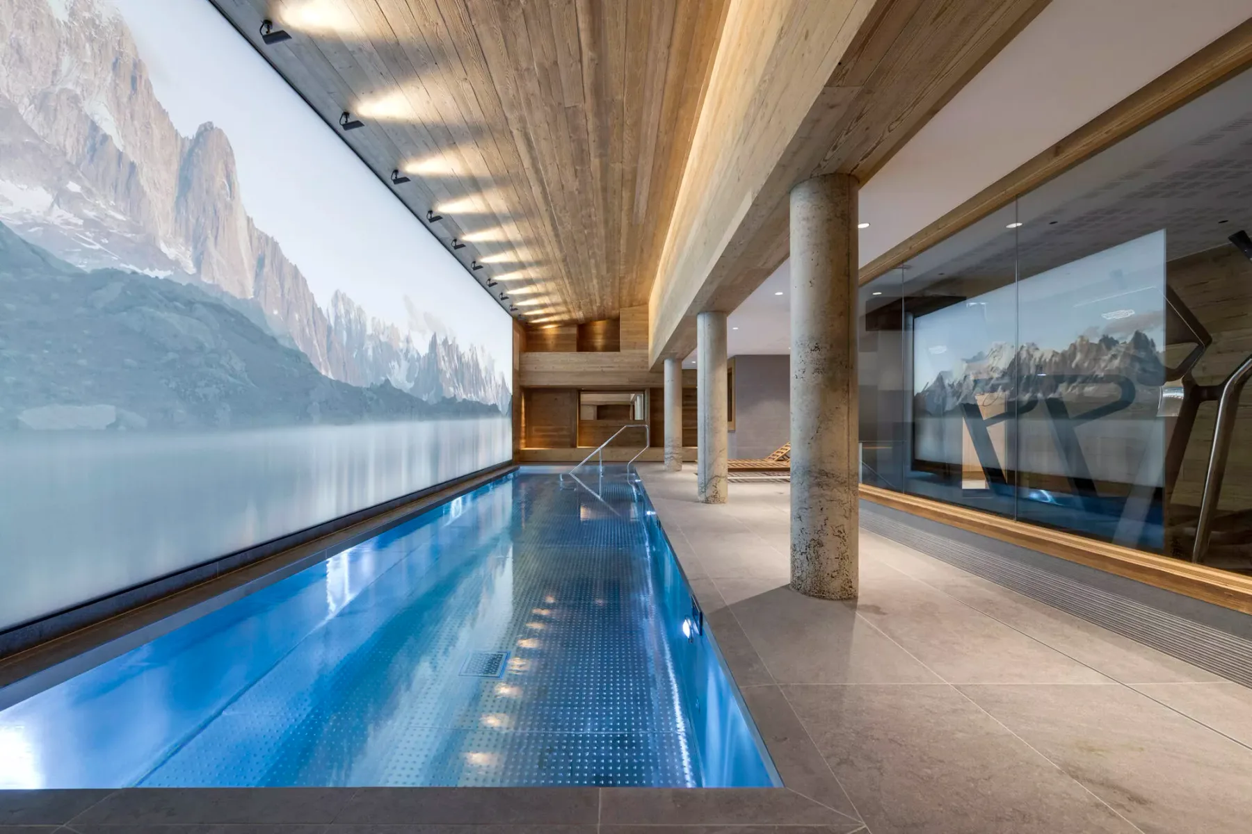 An indoor swimming pool runs beside large windows with mountain views.