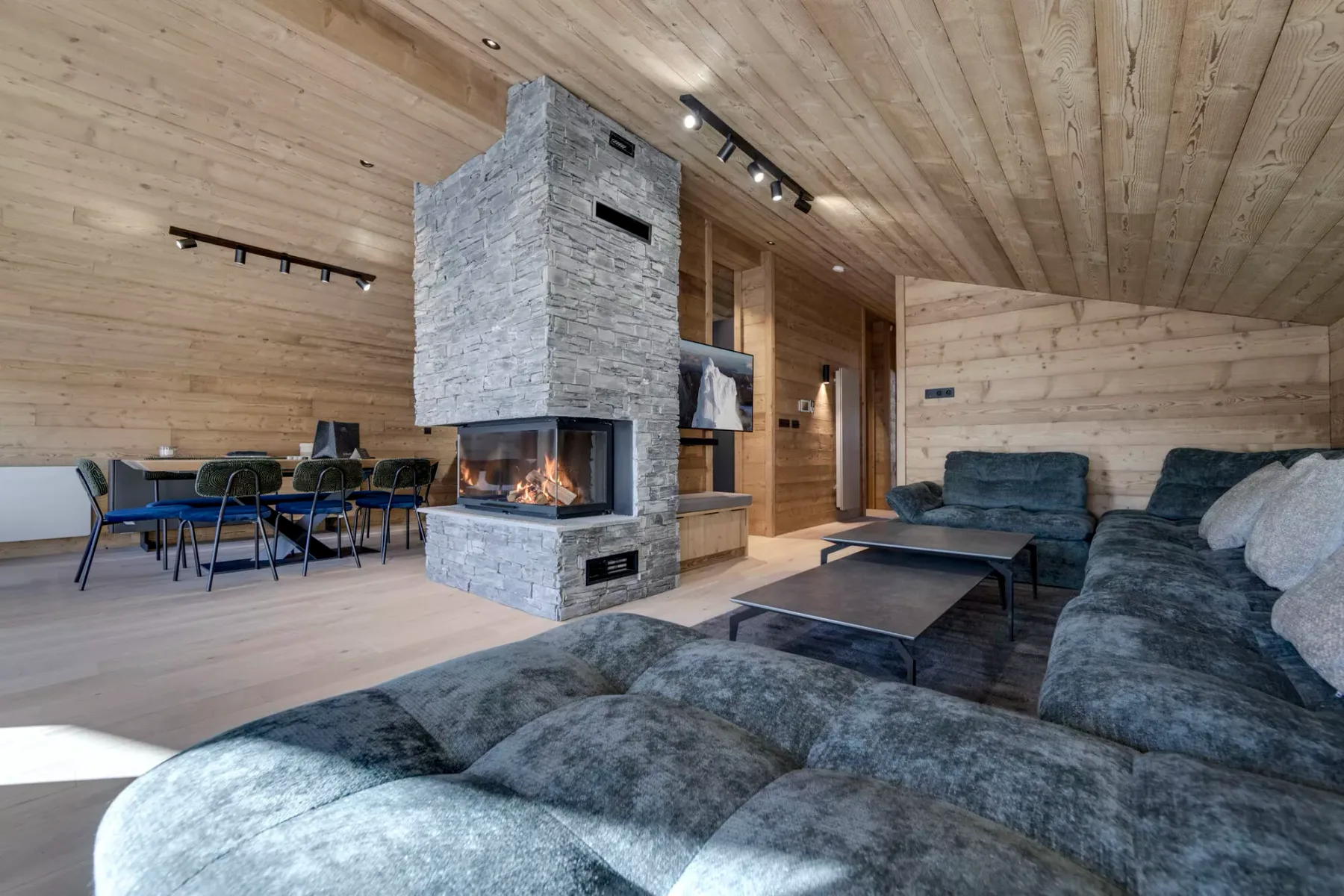 A wood-paneled living room features a stone fireplace and seating area.