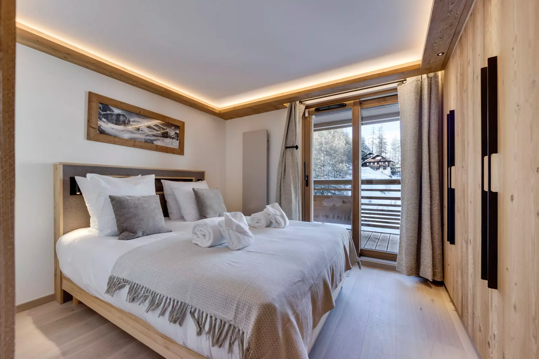 A bedroom with a neatly made bed beside a glass balcony door.