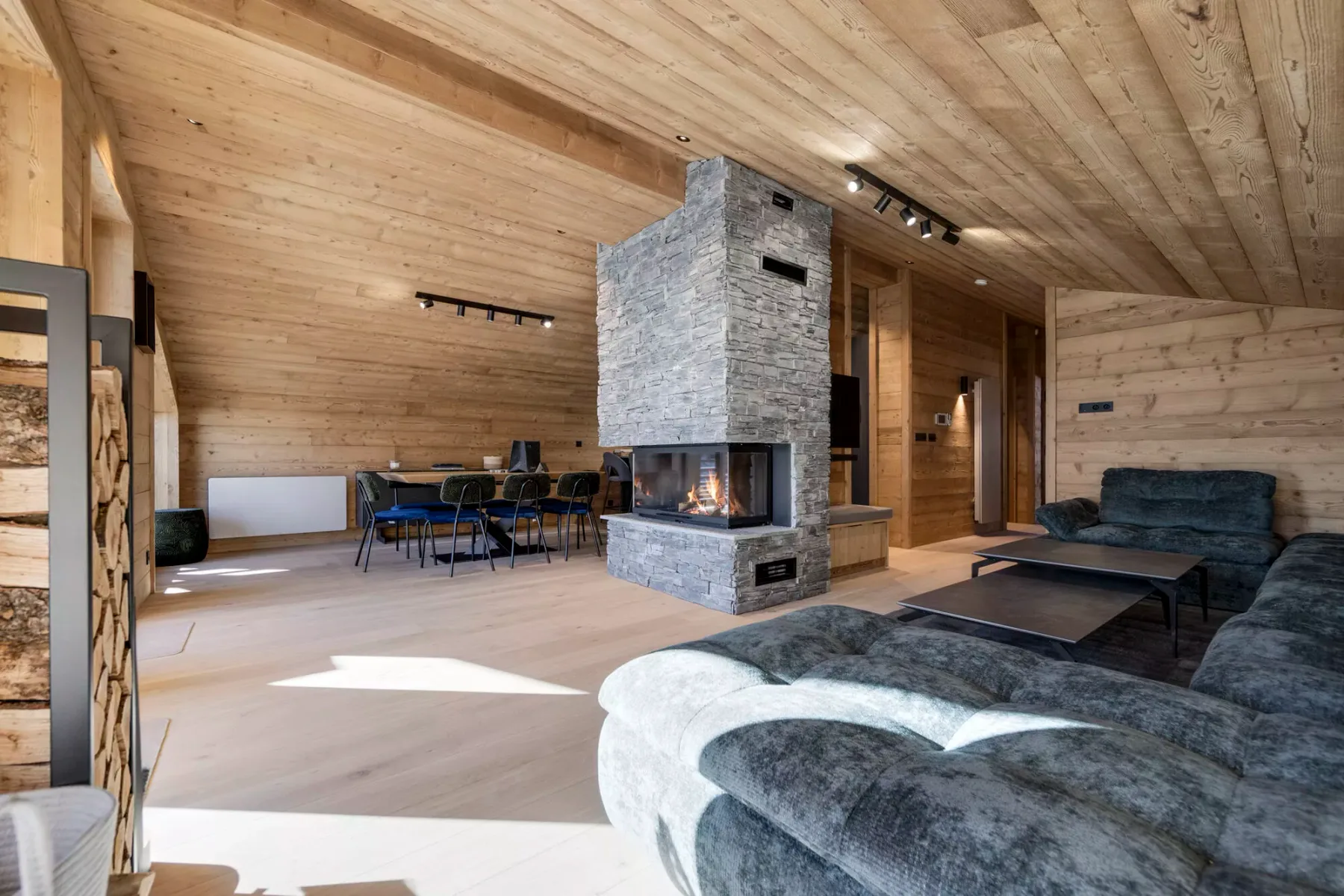 A wood-paneled living room with a stone fireplace and seating area.