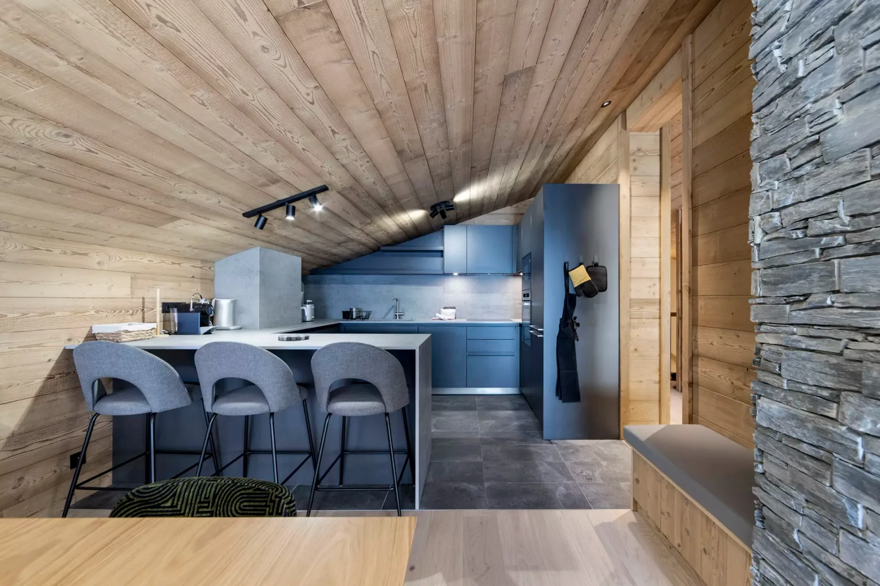A wood-paneled kitchen with a counter, seating, and blue cabinetry.