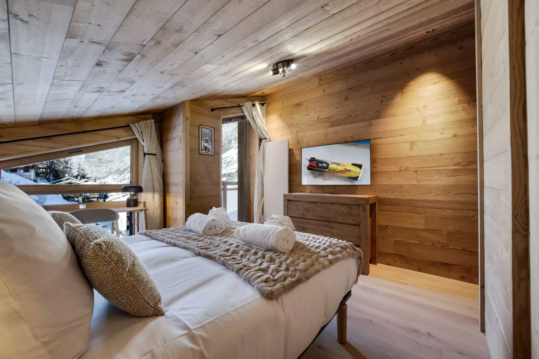 A bedroom with a bed, wooden walls, and a television.