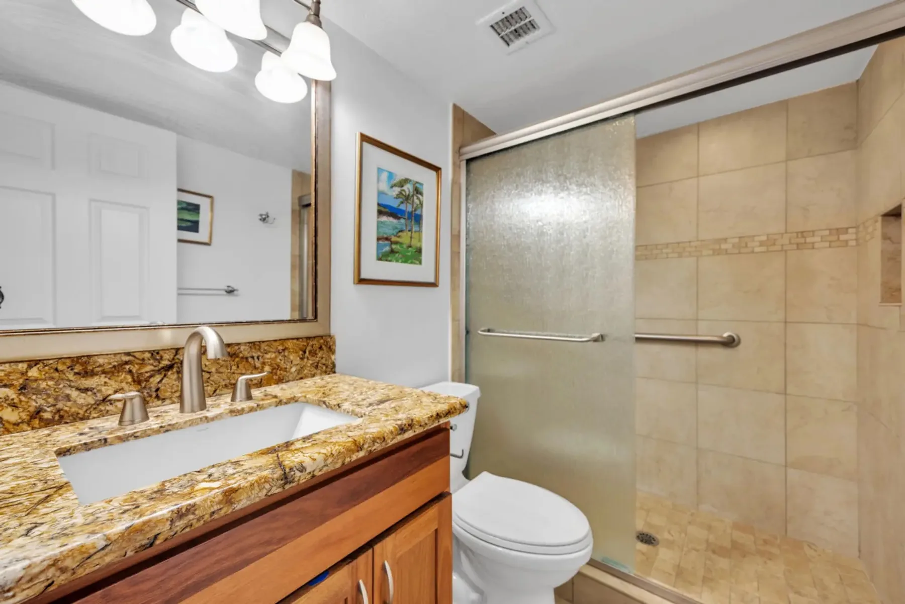 Un baño con un amplio tocador, espejo, inodoro y zona de ducha con azulejos.
