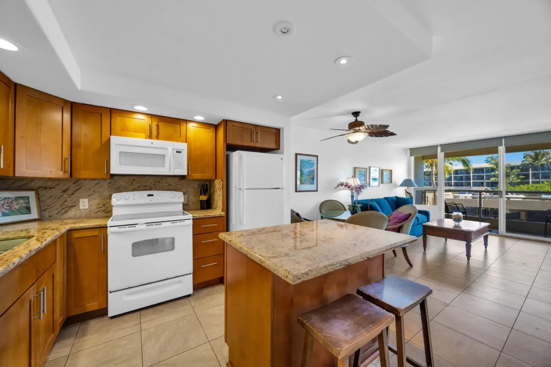 Cocina abierta con sala de estar, una isla y asientos junto a grandes ventanas.