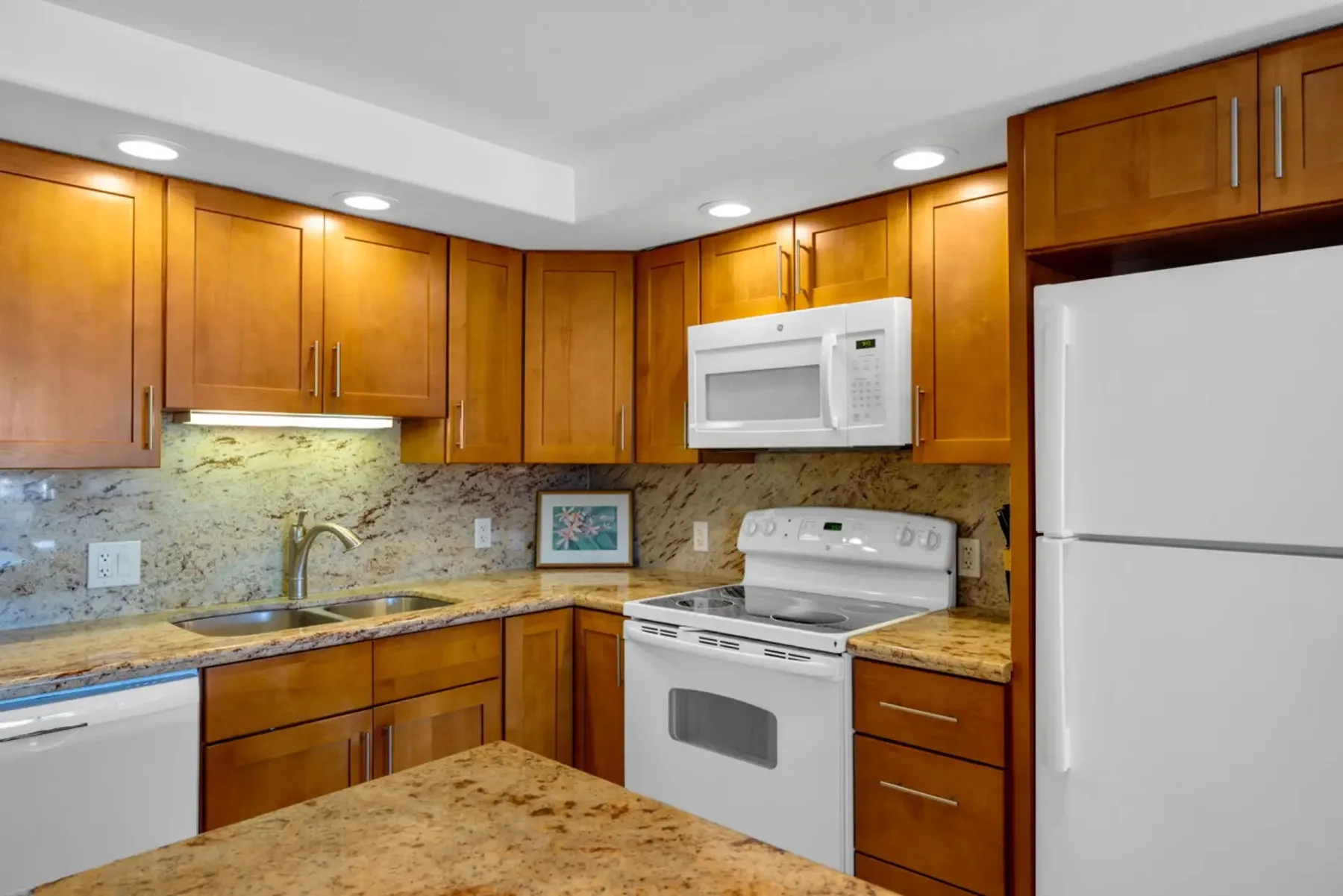 Una cocina con gabinetes de madera, encimera y electrodomésticos blancos.
