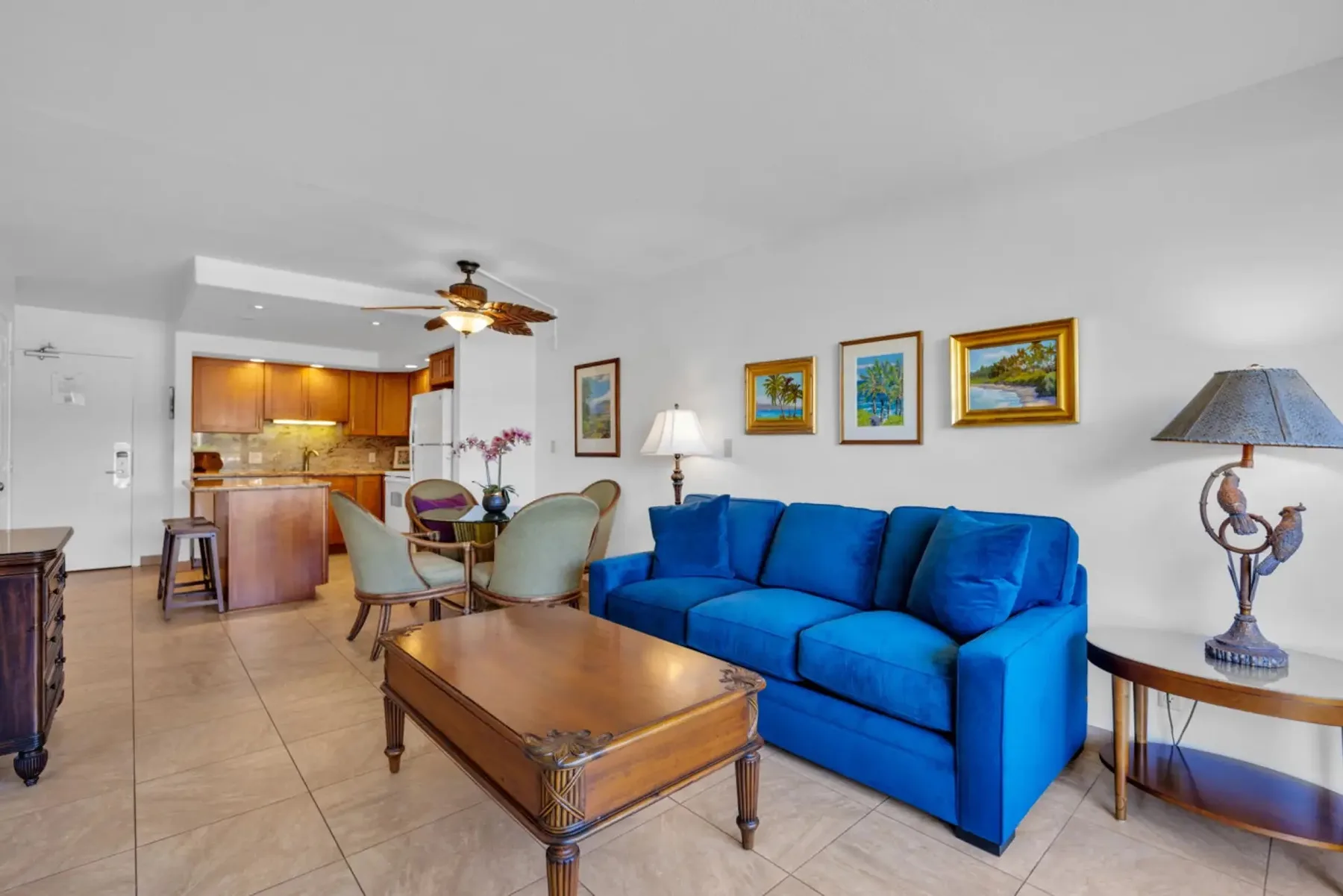 Sala de estar con asientos azules, una mesa de centro y una cocina abierta.