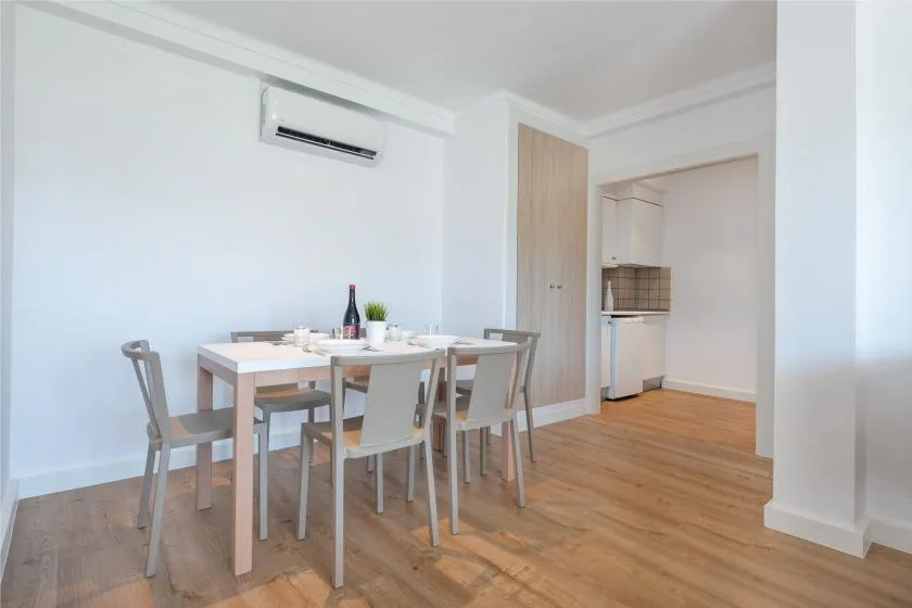 A dining area with a wooden table and chairs beside an open kitchen.