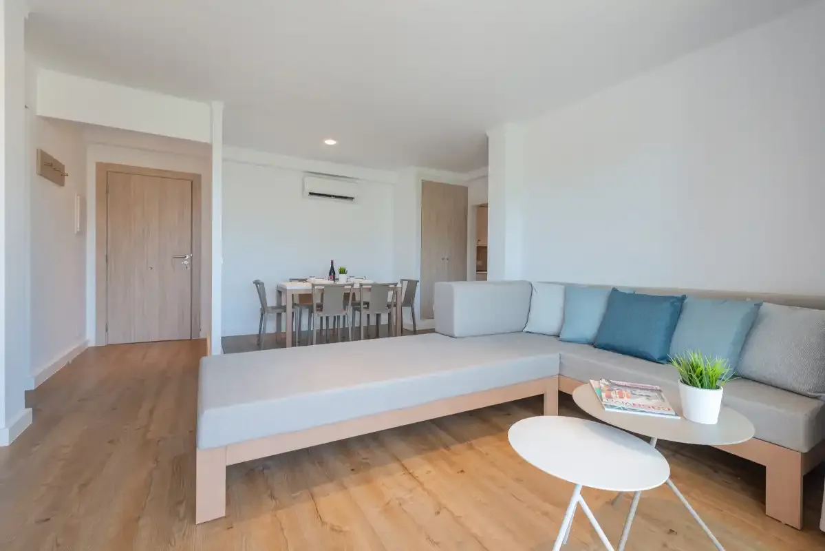 A bright living and dining area with a sectional seating area and coffee tables.