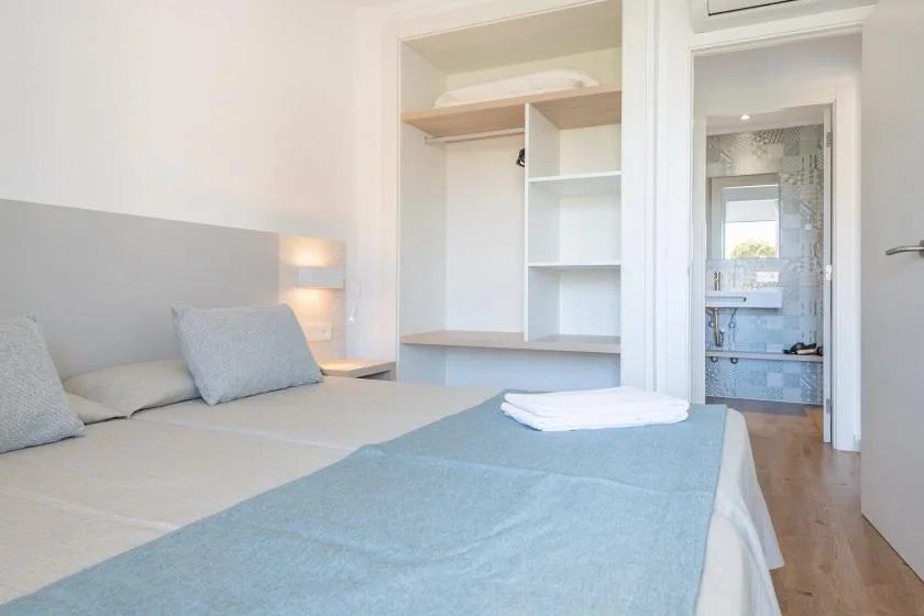 A bedroom with a neatly made bed and built-in shelving.