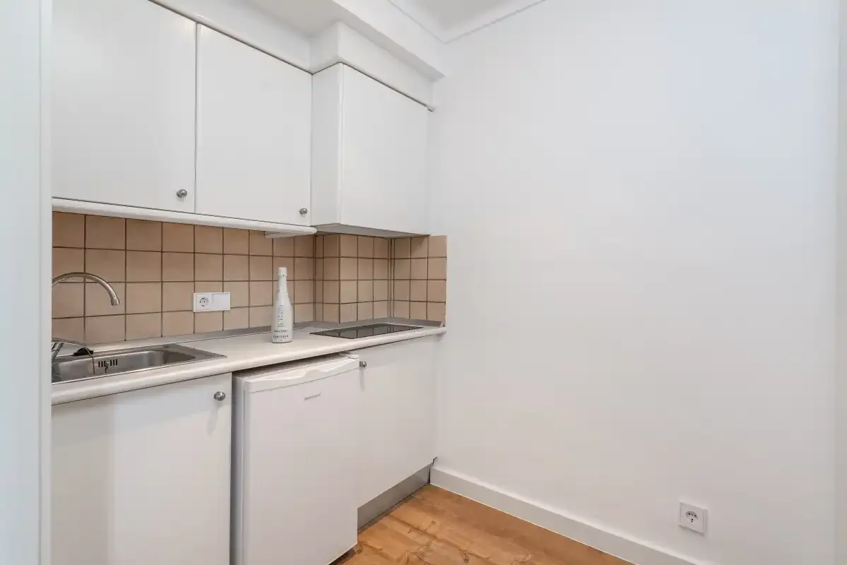 A compact kitchen with white cabinets, a tiled backsplash, and a countertop.