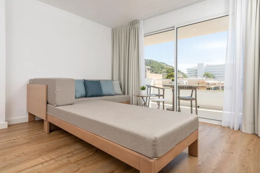 A bright sitting area with a low upholstered daybed beside a large window.