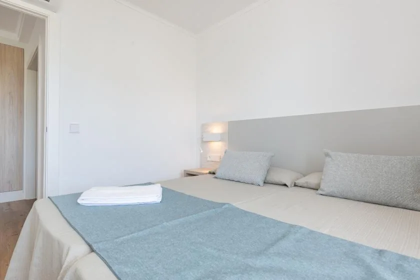 A bedroom with a bed dressed in pale linens and a blue coverlet.