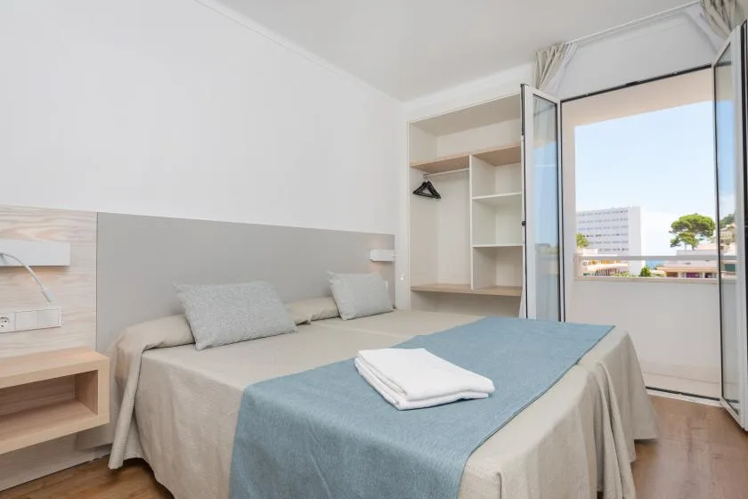 A bedroom with a made bed and an open balcony door.