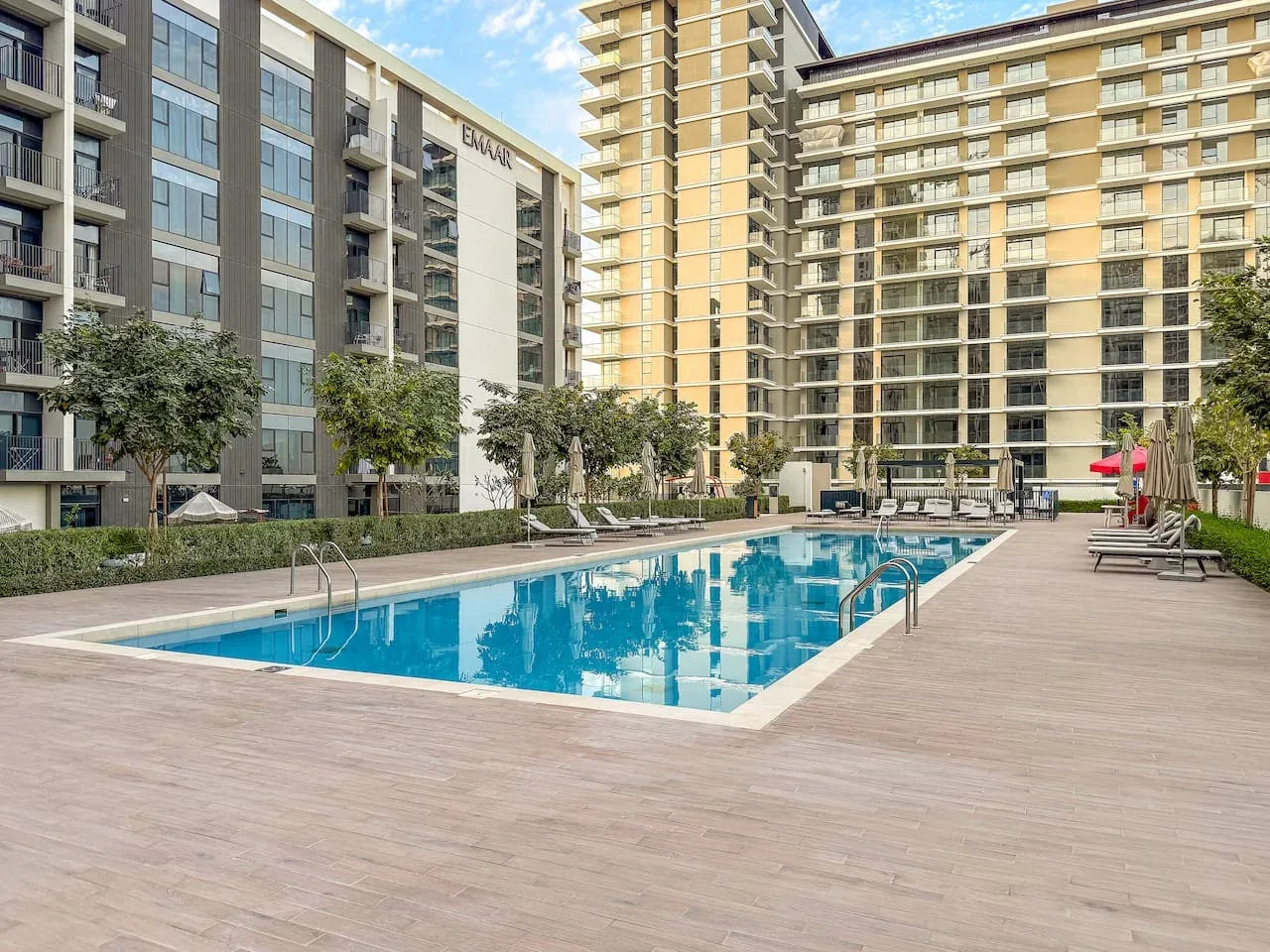 An outdoor swimming pool sits in a courtyard surrounded by apartment buildings.