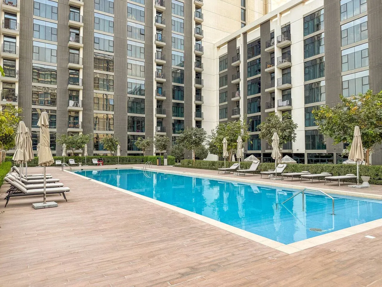 A swimming pool sits in a courtyard surrounded by tall apartment buildings.