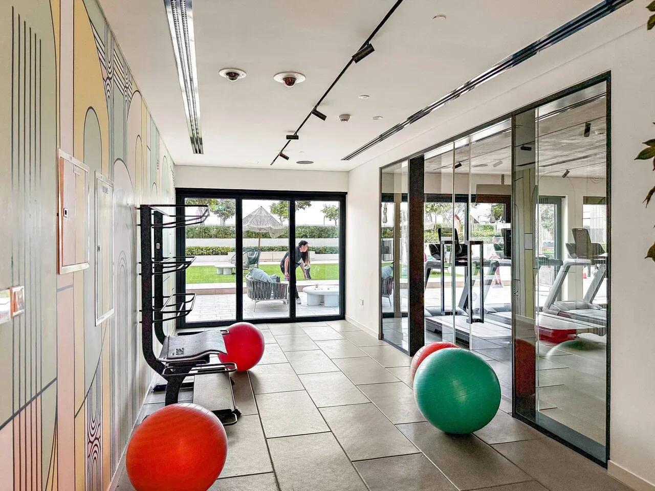 A bright indoor exercise area with glass walls and colorful exercise balls.