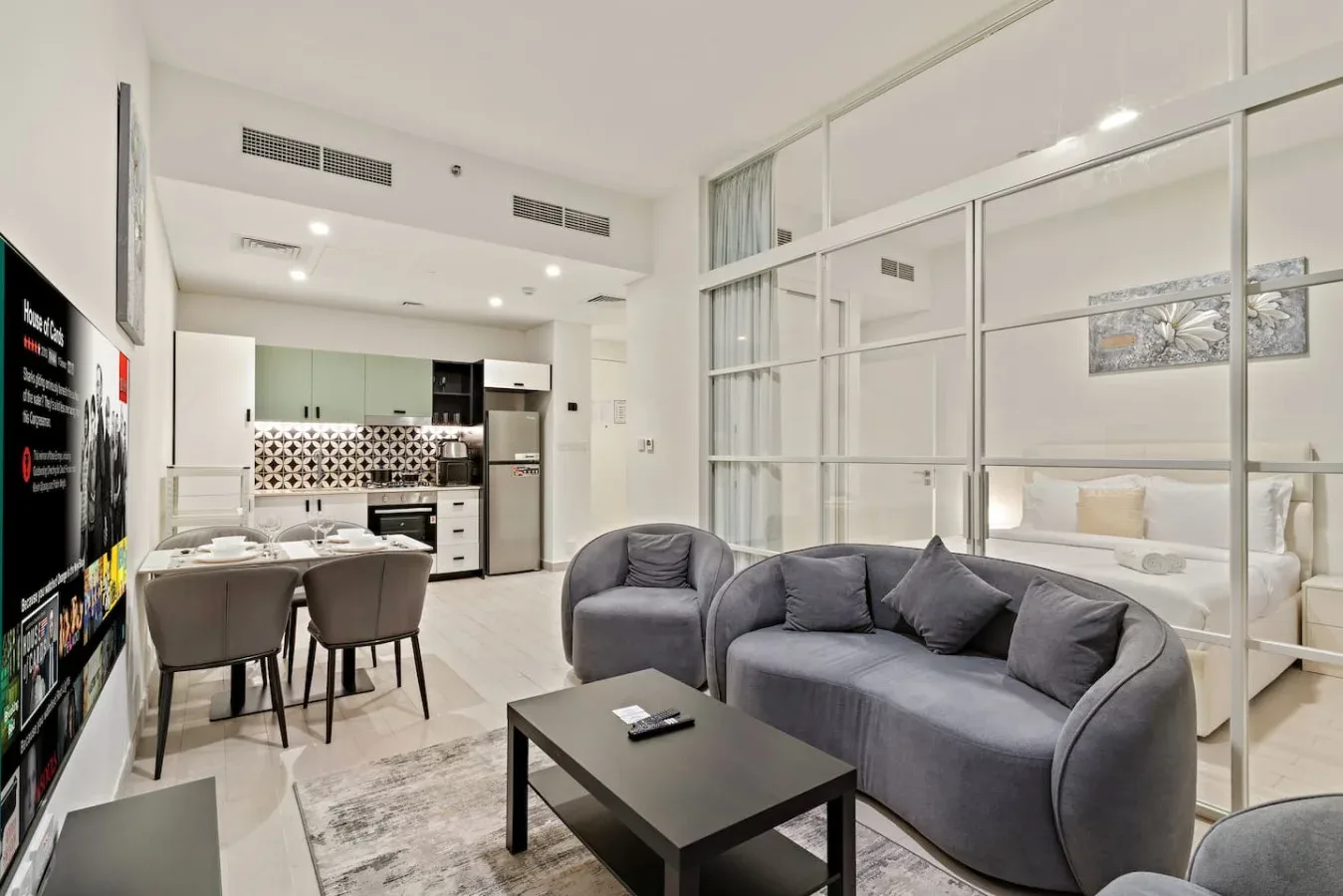 A modern living area with gray seating, a coffee table, and an open kitchen.