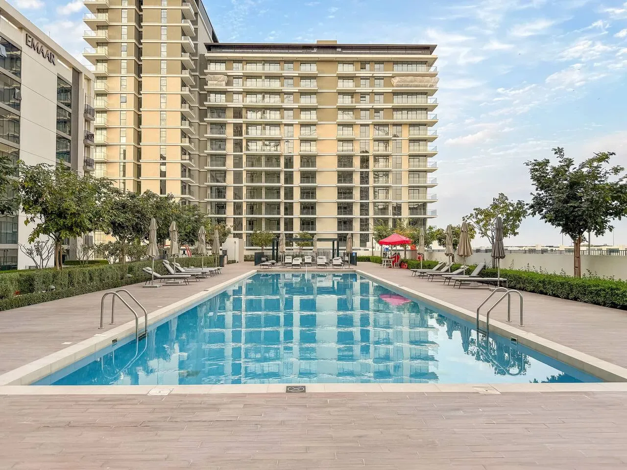 Una piscina al aire libre está frente a un edificio moderno de gran altura.