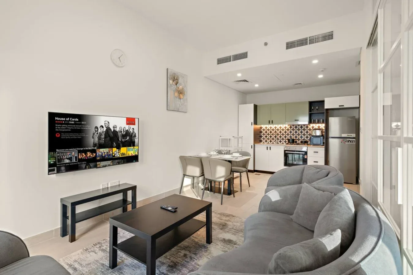 A bright living room opens onto a kitchen, with seating and a coffee table.
