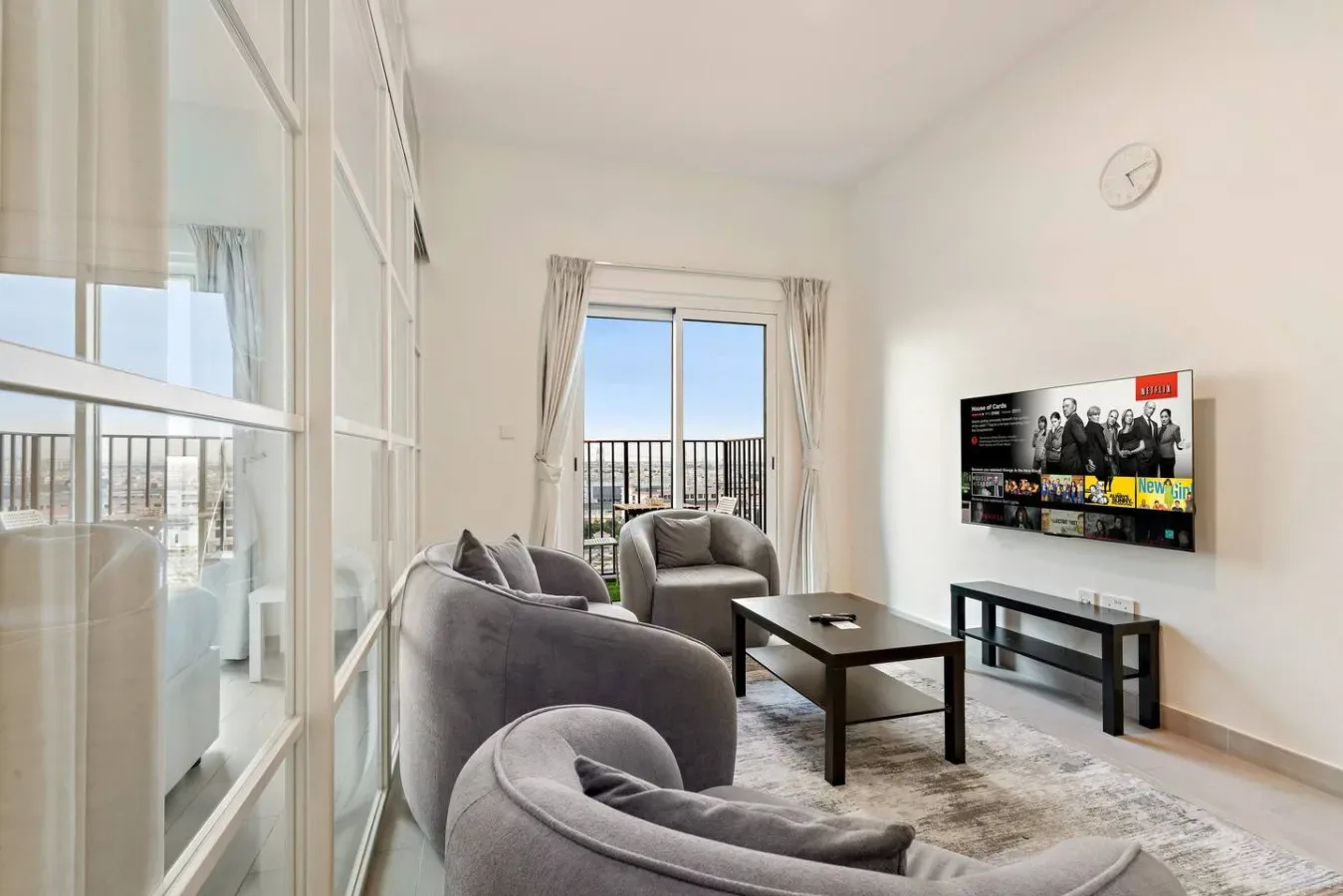 A bright living room with seating, a coffee table, and a television.