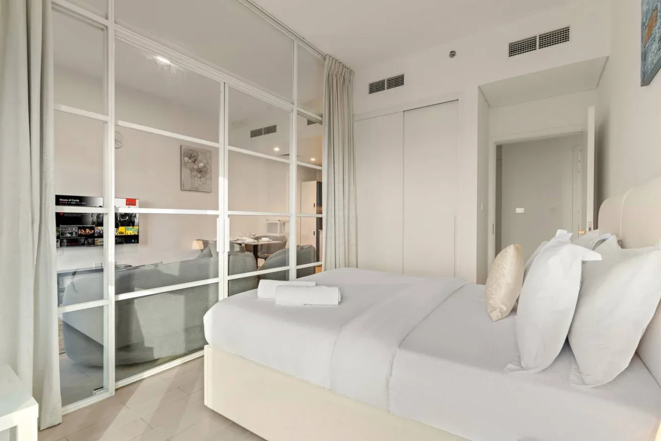 A bright bedroom with a bed beside a glass partition.