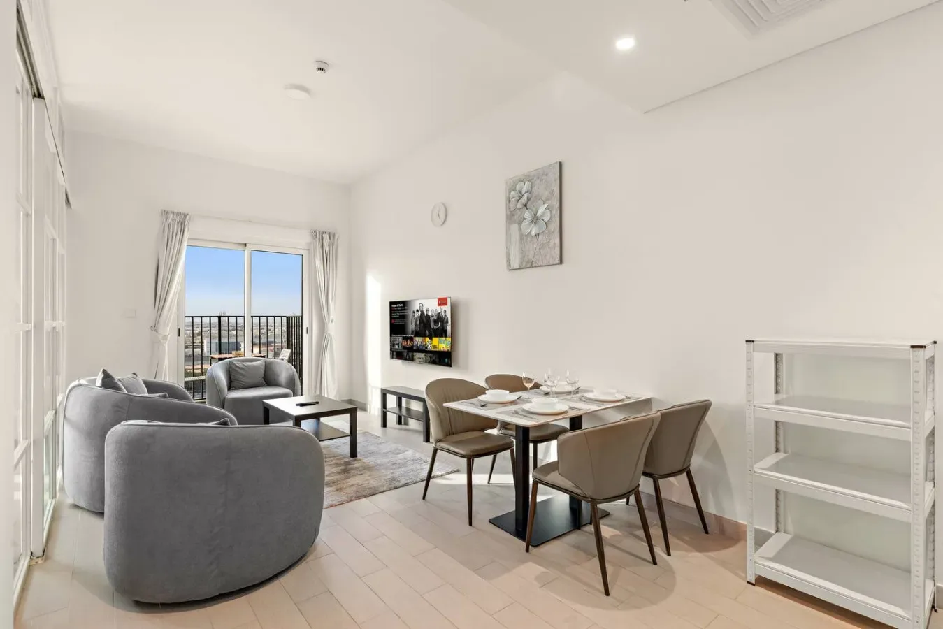 A bright living and dining area with seating, a dining table, and balcony doors.