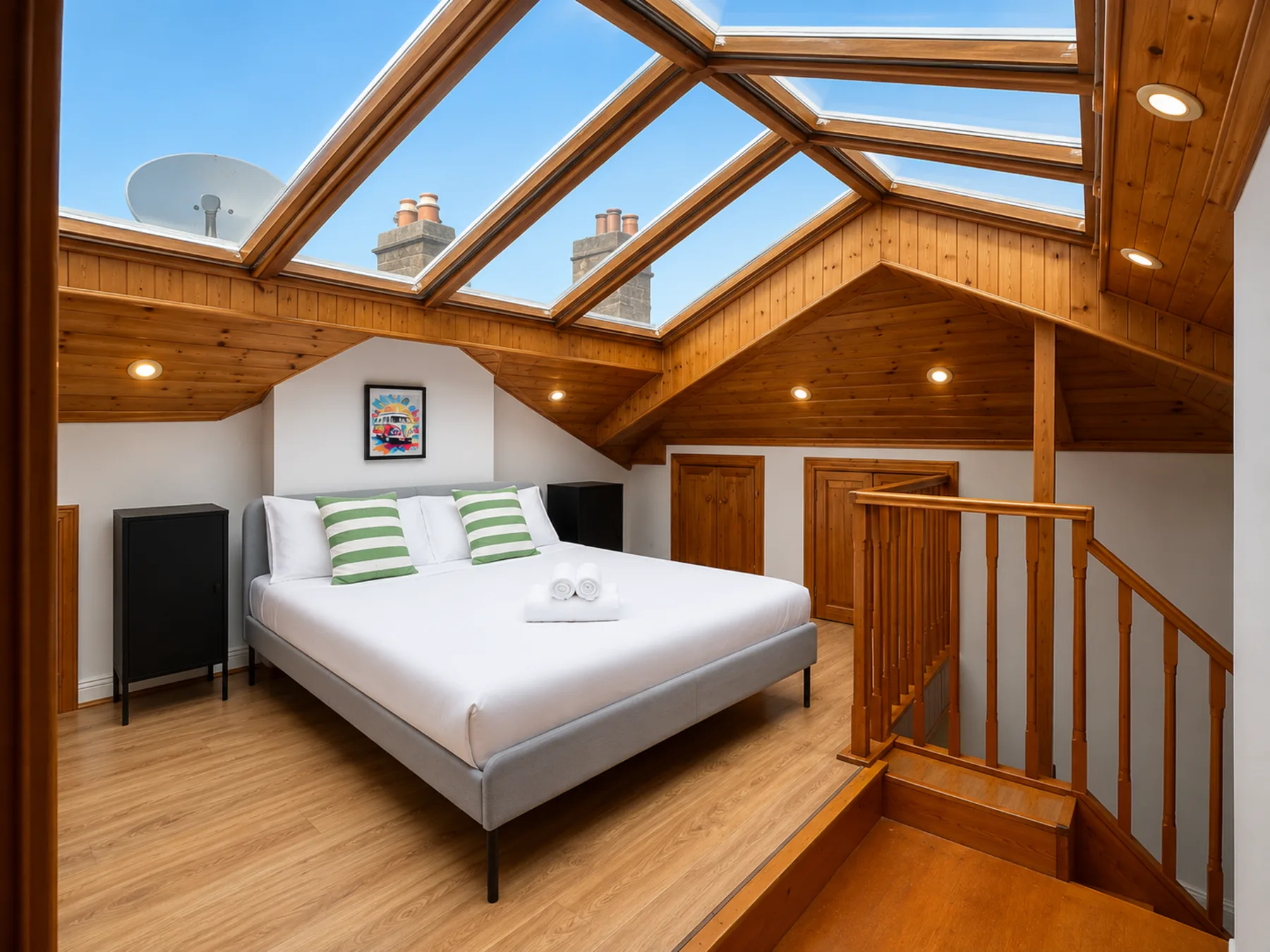 A bedroom with a bed beneath a large skylight.