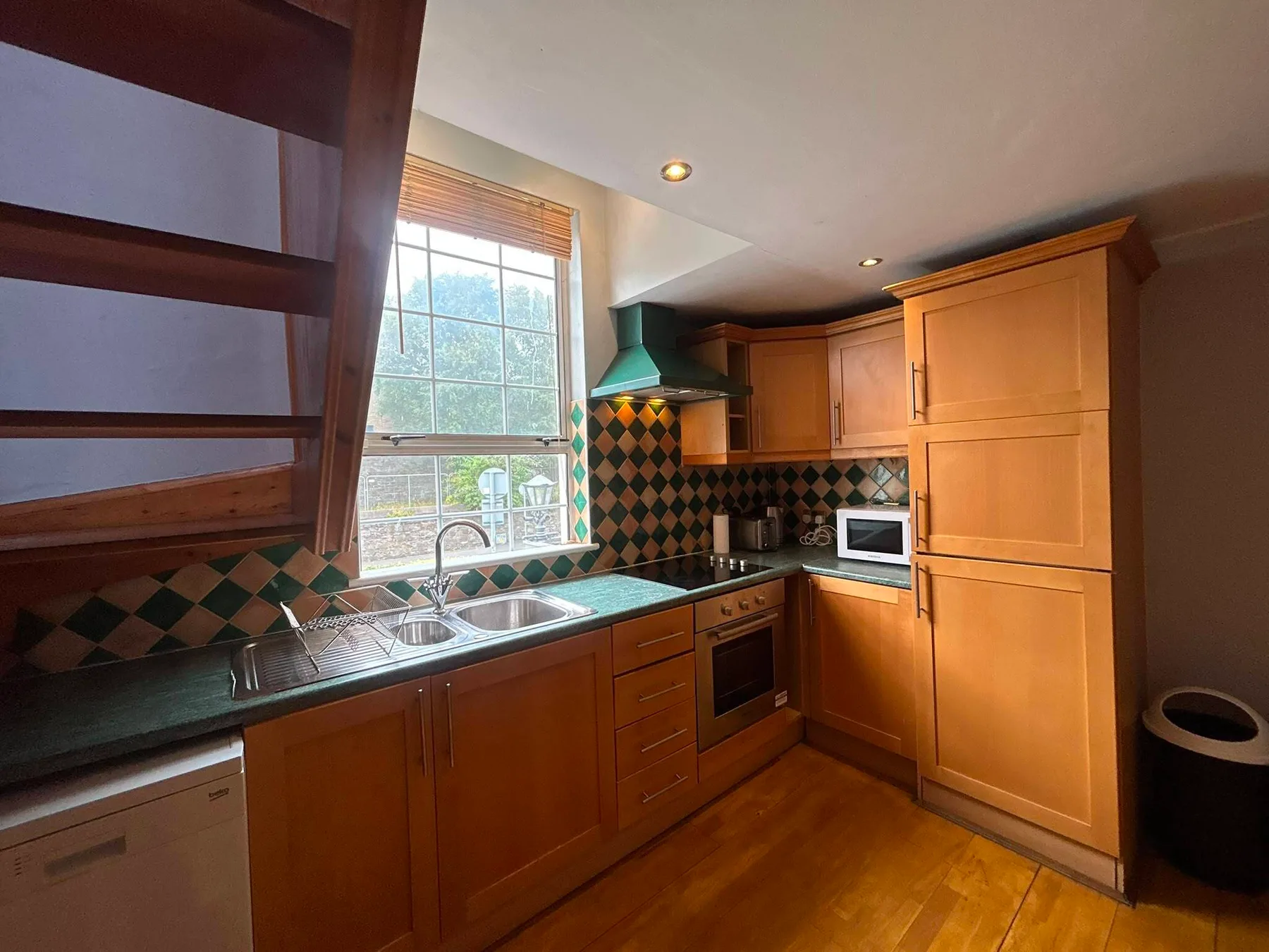 A kitchen with wooden cabinets, a sink, and a tiled backsplash.