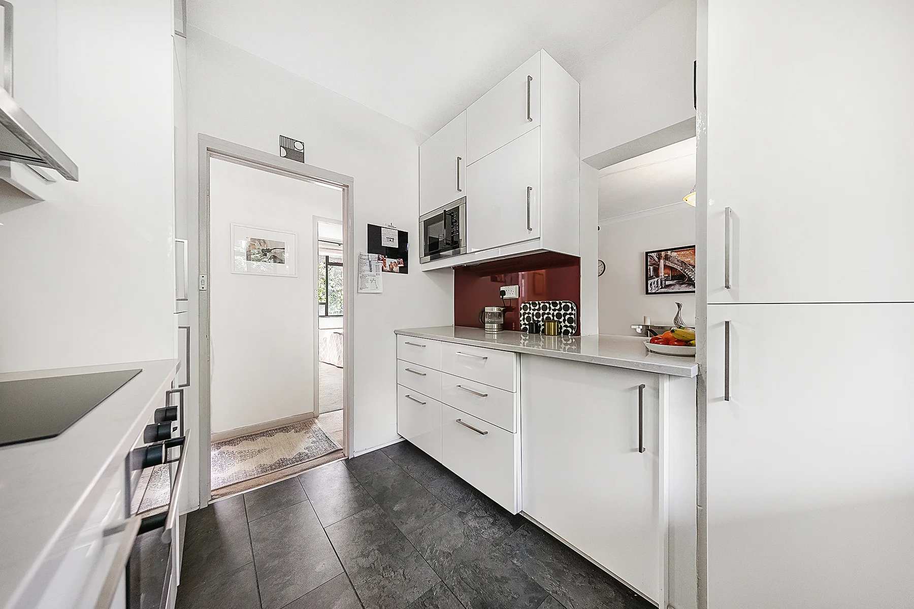 A bright kitchen with white cabinets, a countertop, and dark flooring.