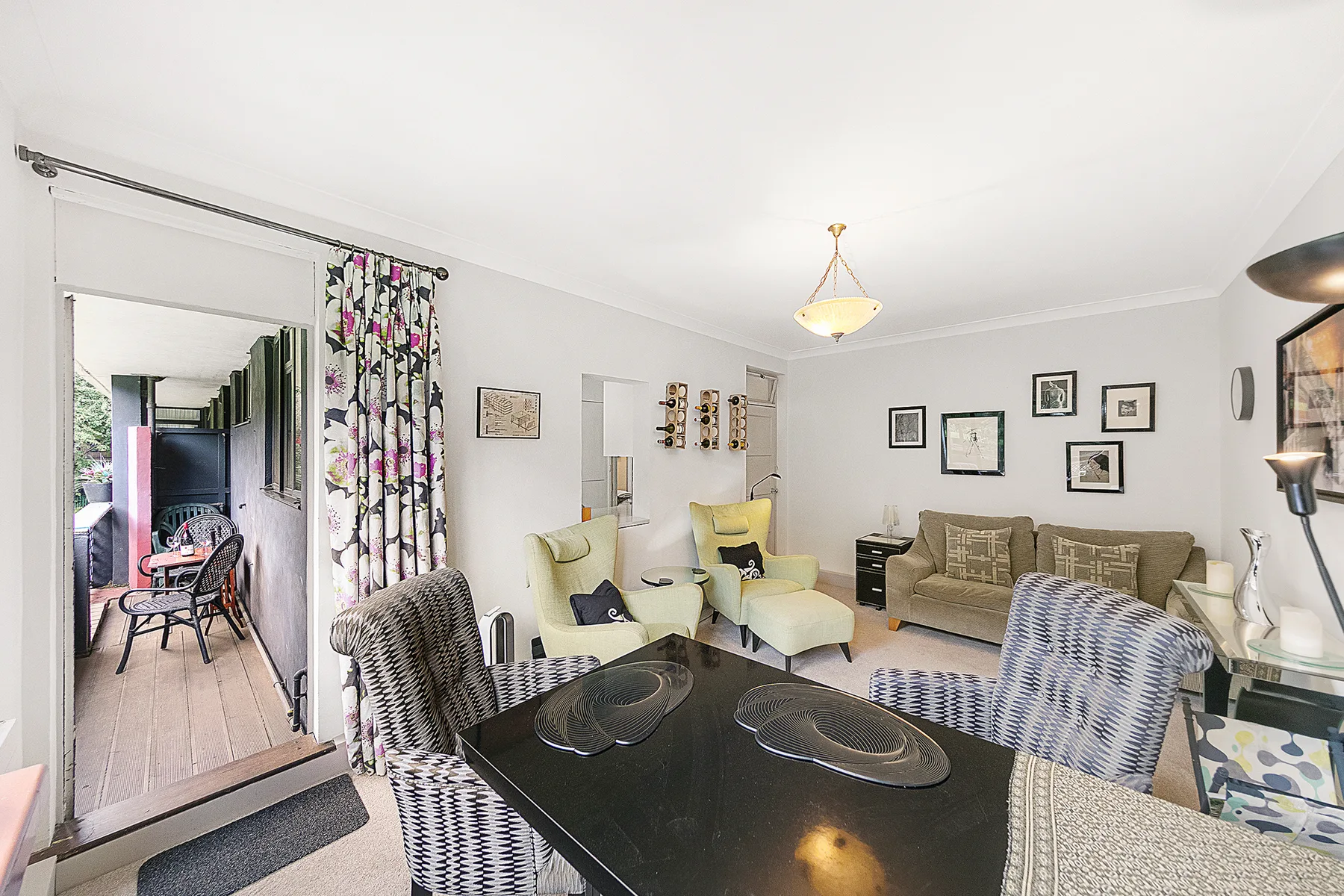 A bright living room with a dining table, seating, and framed wall art.