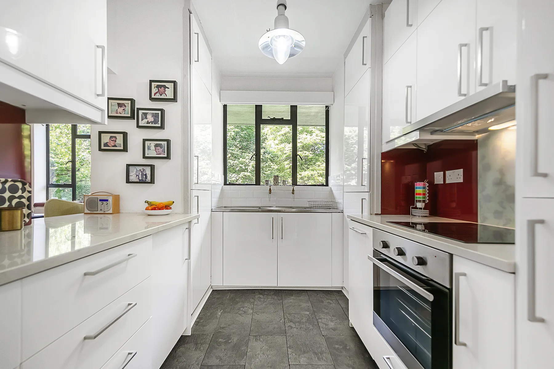 A bright white kitchen with a central sink and a built-in oven.