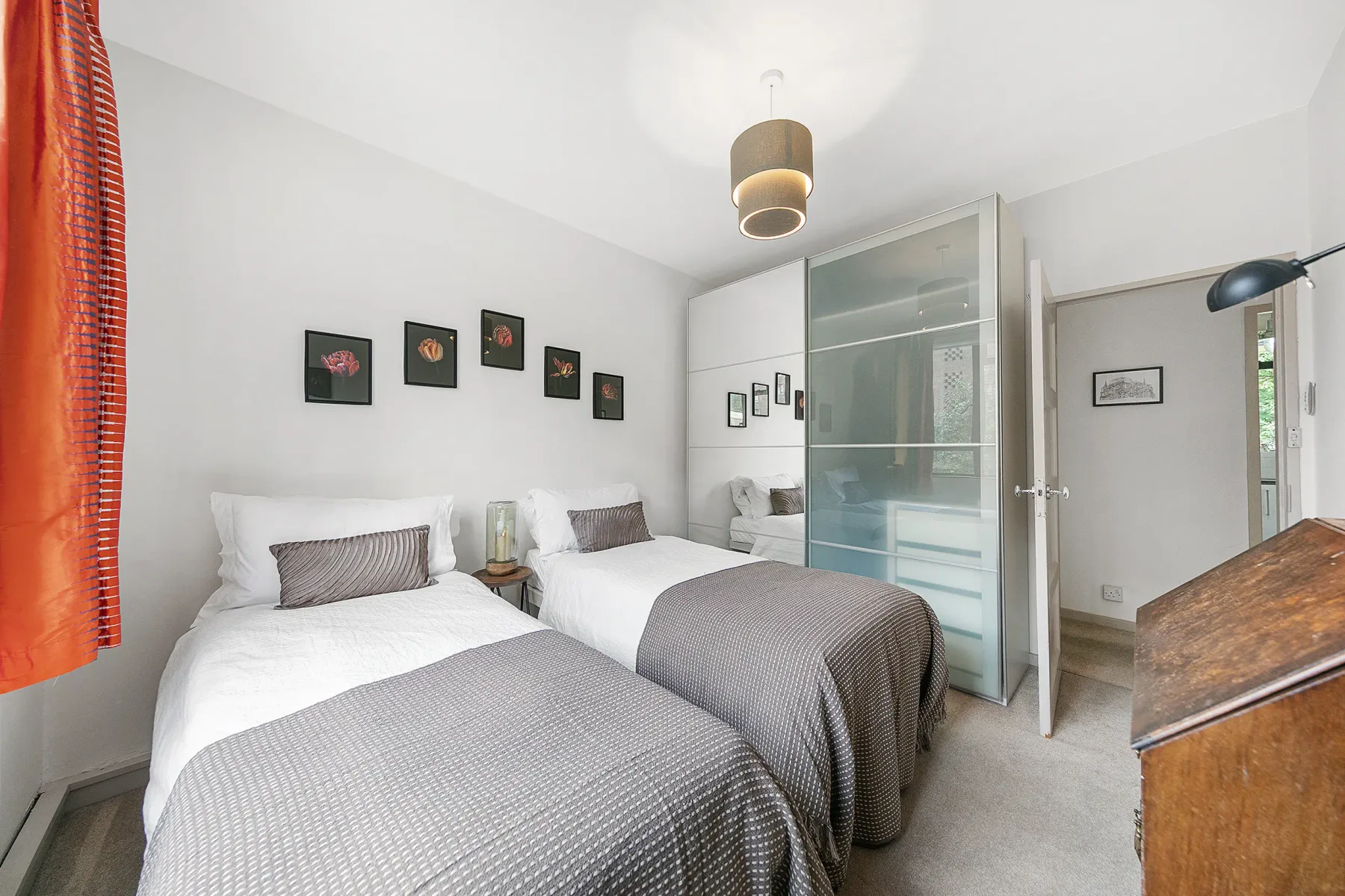 A bright bedroom with two beds and a glass-paneled partition.