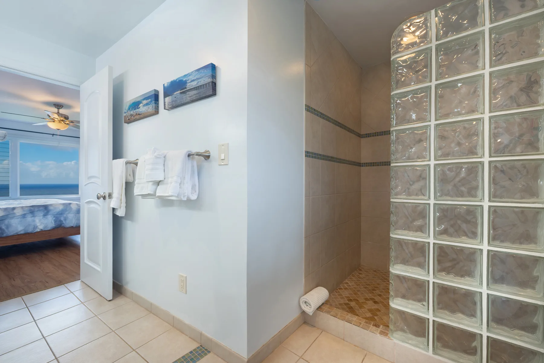 Un baño con una ducha revestida de azulejos junto a una pared de bloques de vidrio.