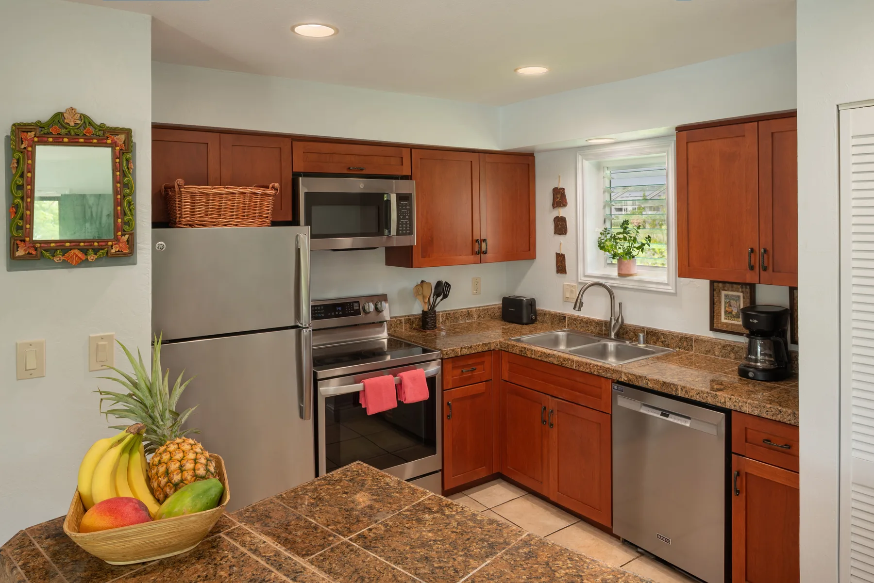 Una cocina con gabinetes de madera, electrodomésticos de acero inoxidable y una encimera de azulejos.