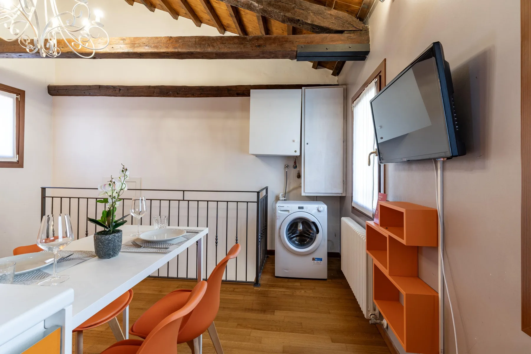 Comedor con una mesa, asientos y un televisor montado en la pared.