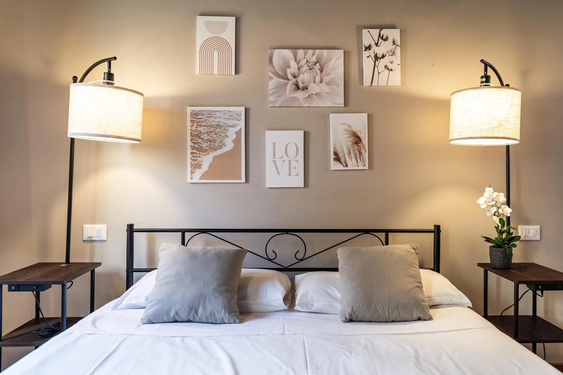 Un dormitorio con una cama bien hecha, mesas de noche y cuadros en la pared.