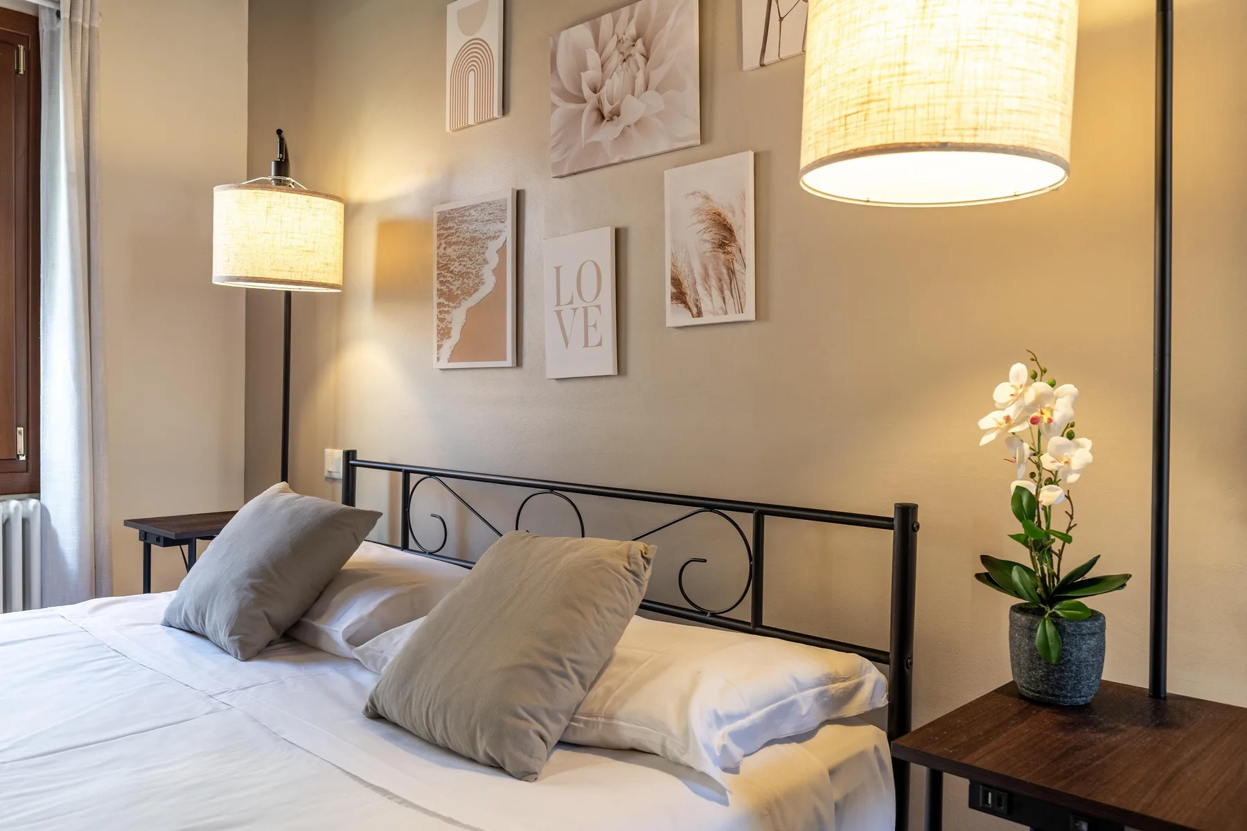 Un dormitorio con una cama, cuadros en la pared e iluminación colgante cálida.