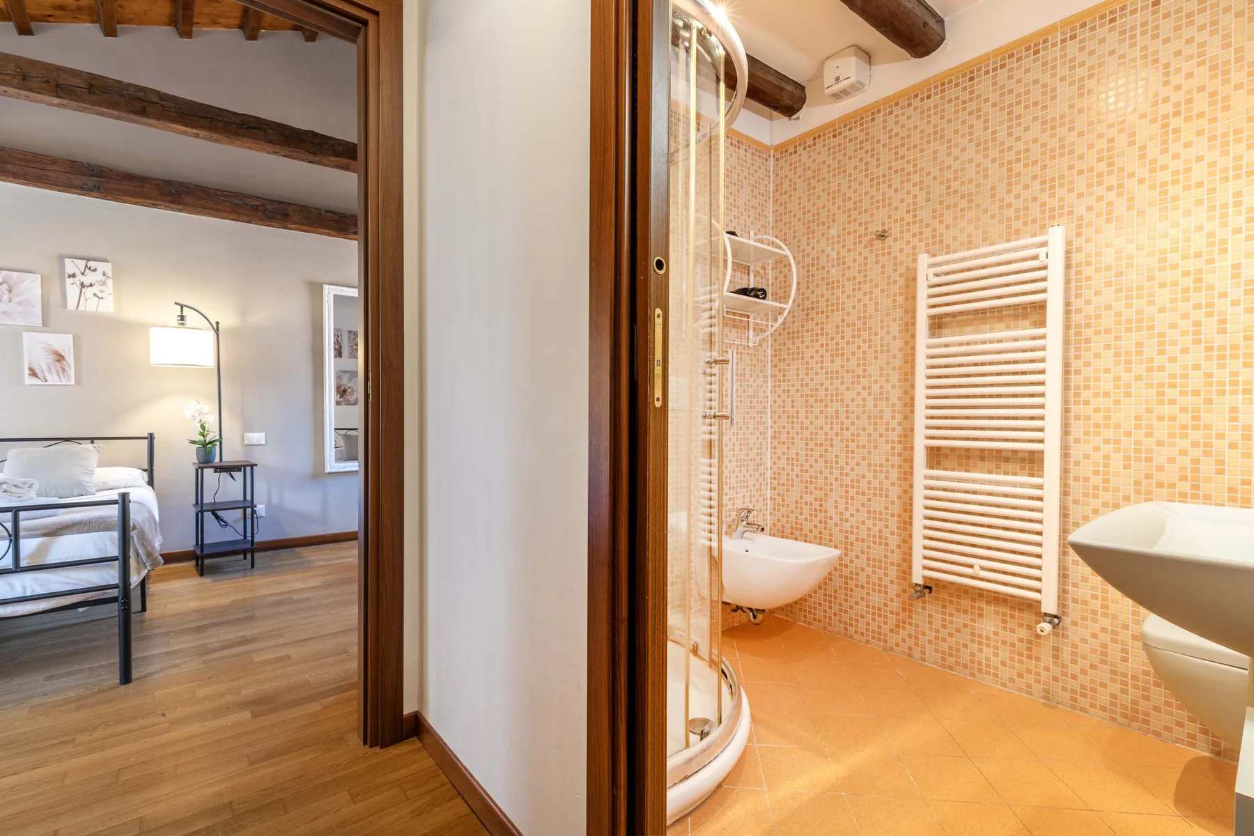 Un baño con una ducha curva y un toallero calefactable en la pared.