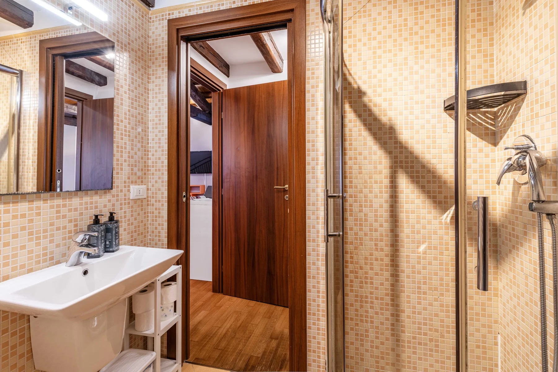 Un baño alicatado con lavabo, espejo y ducha.