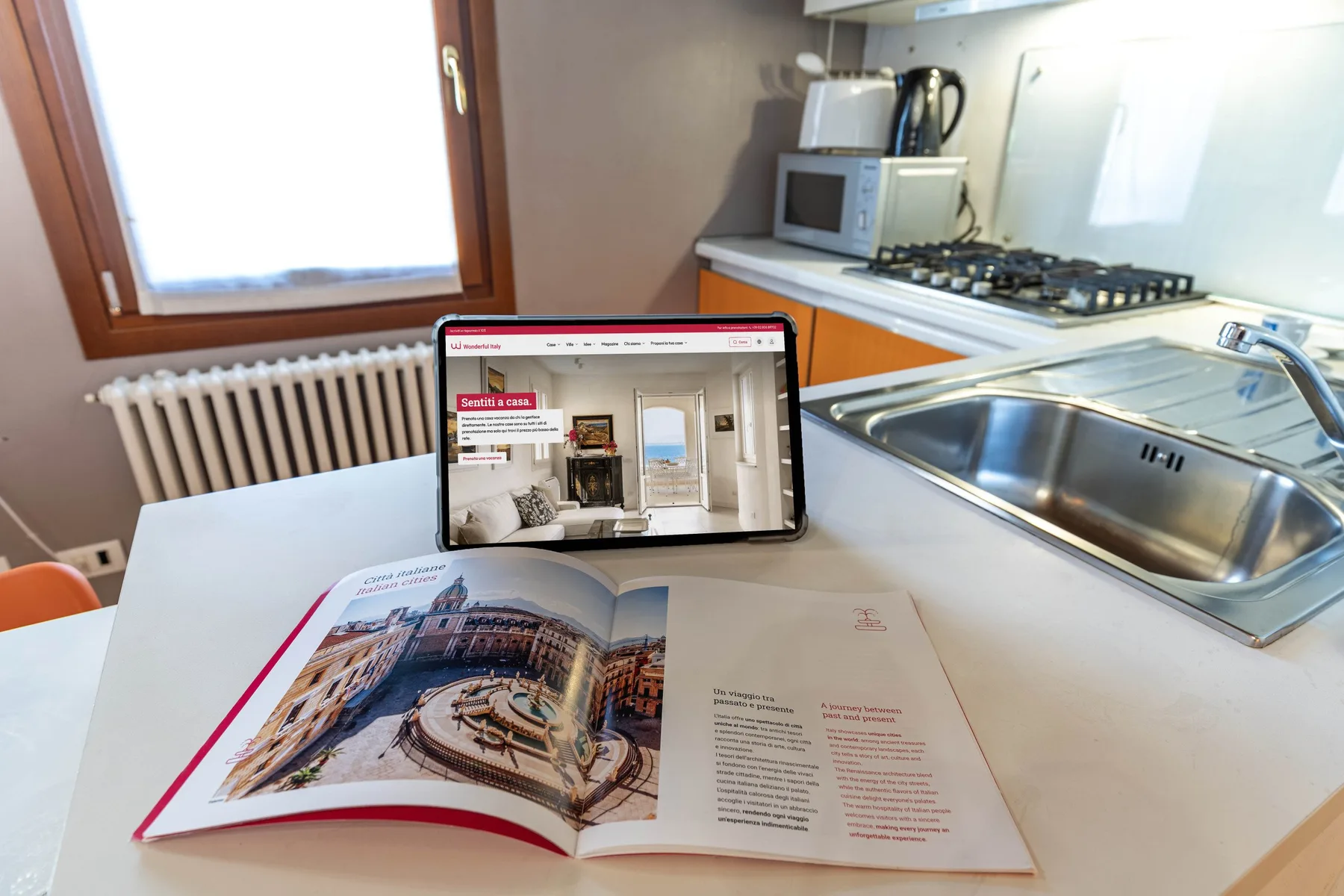 Una encimera de cocina con fregadero, placa de cocción y un folleto abierto.