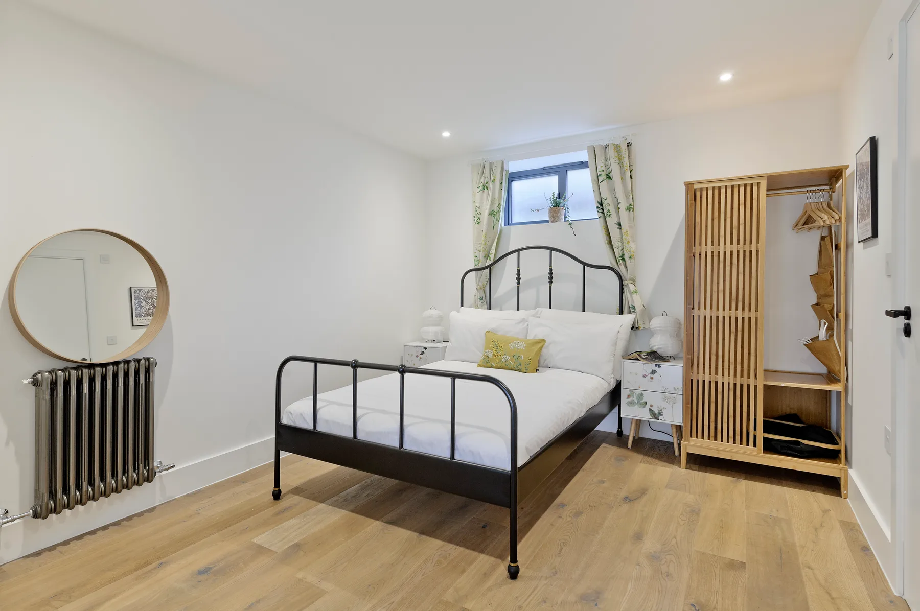 A bedroom with a metal bed, white bedding, and a wardrobe.